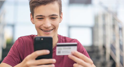 teen boy boy on his phone holding a debit card week 3