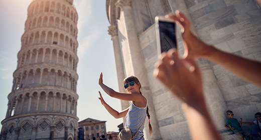Woman posing lik she is holding up the Tower of Pisa while her friend takes a photo