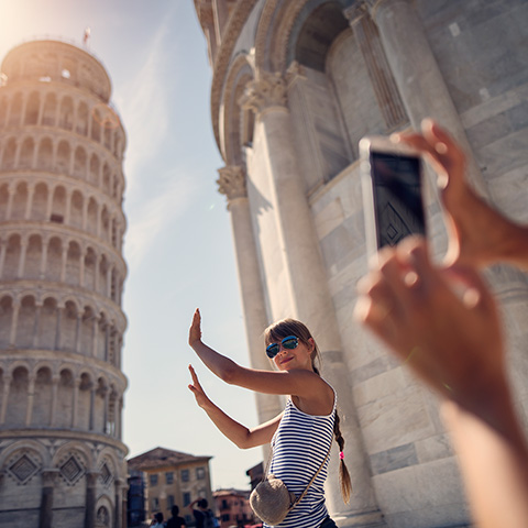 Woman posing lik she is holding up the Tower of Pisa while her friend takes a photo